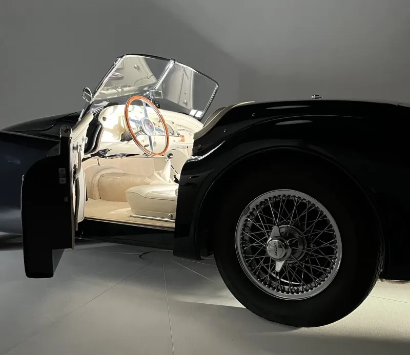 Détail de l'habitacle et de la roue à rayons d'une Jaguar XK, lumière rasante