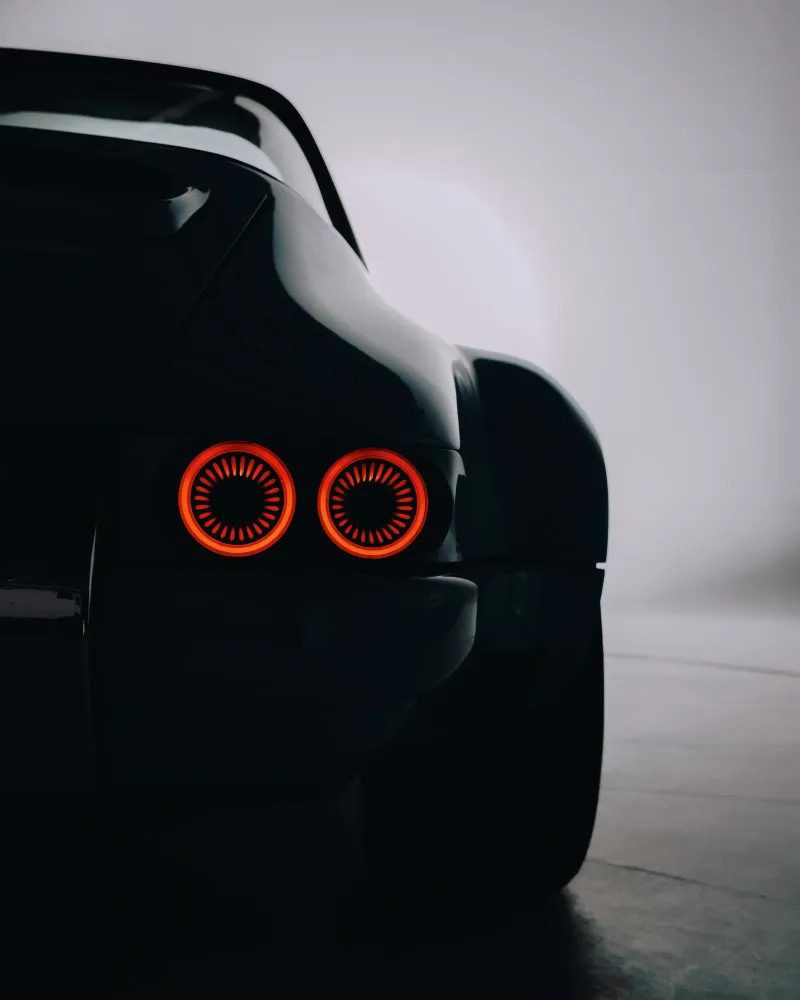 Feux arrière circulaires d'une Porsche Targa noire en contre-jour dans la brume du studio