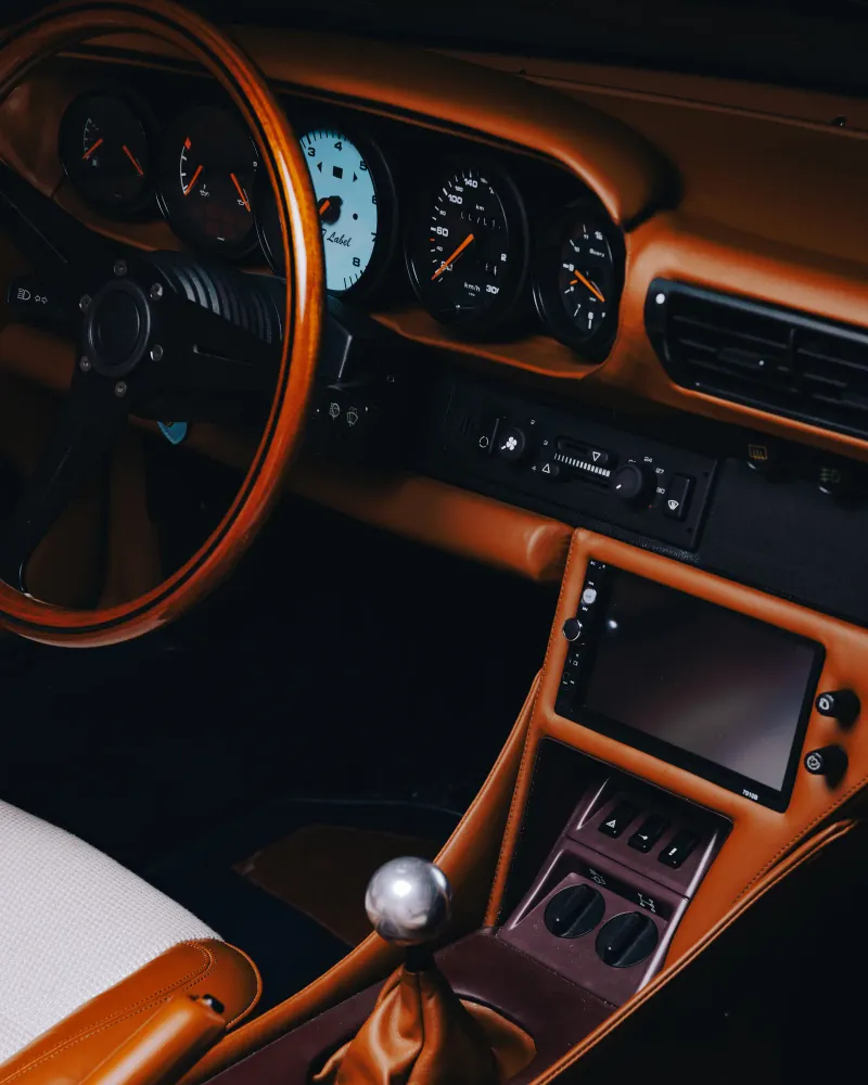 Habitacle d'une Porsche Targa restaurée : volant en bois, cuir cognac et compteurs