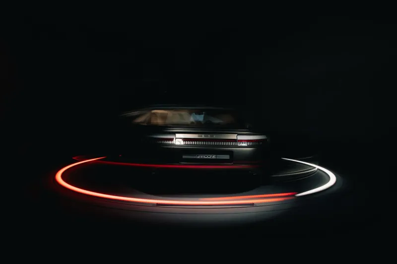 Arrière d'une Porsche Nardone sur le plateau tournant, pose longue : plaque Nardone et traînées de lumière rouge