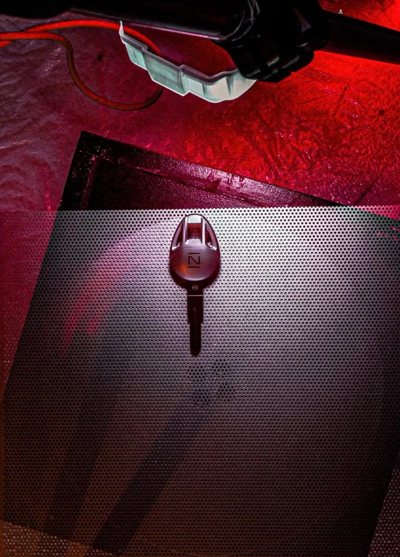 Clé Nardone posée sur une plaque perforée, éclairée en rouge